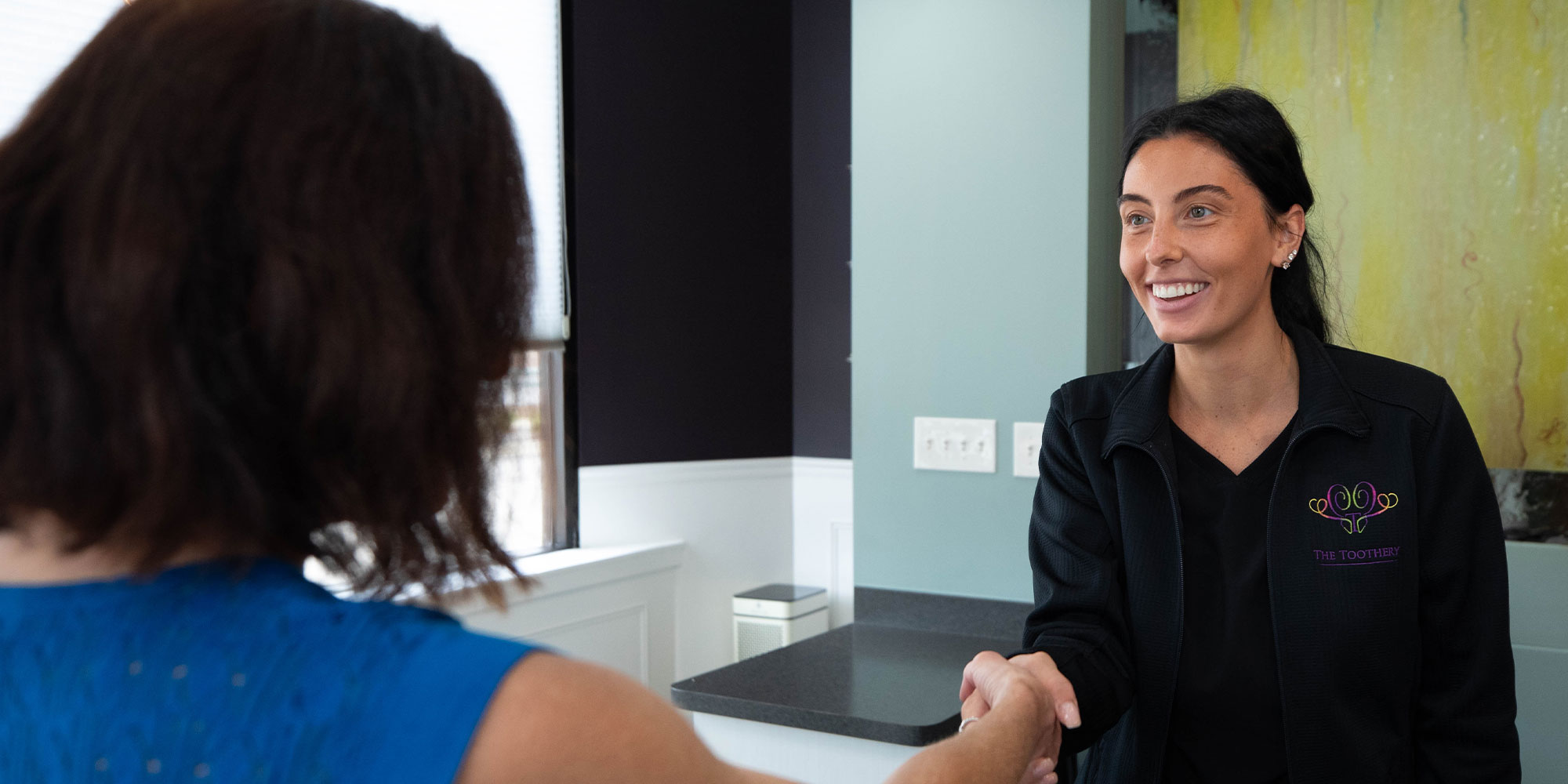 staff member helping dental implant patient at the front desk of the dental practice